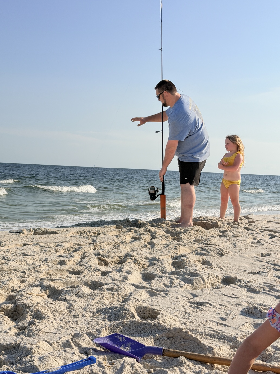 Father and daughter checking a surf rod beside the Gulf