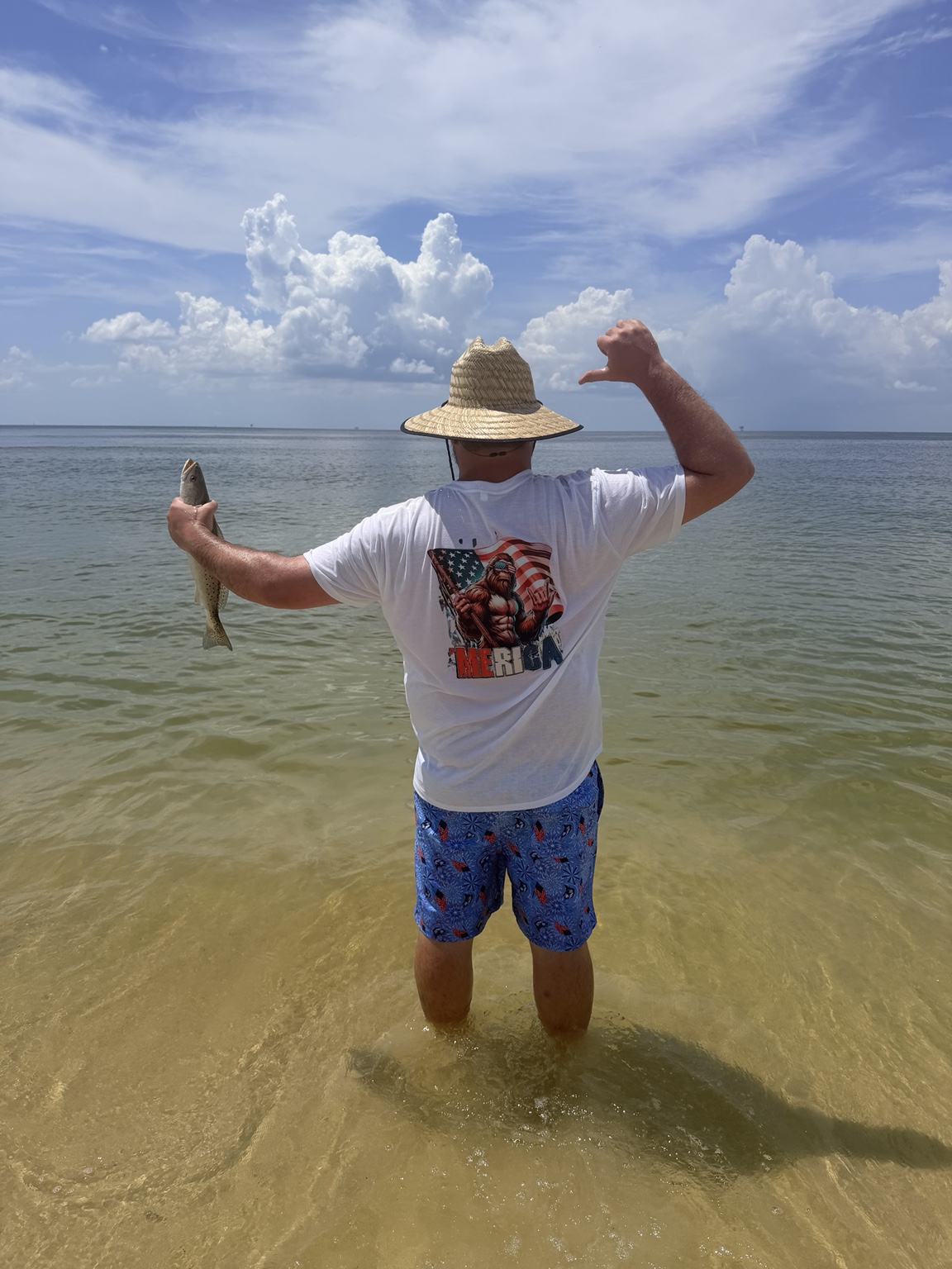 Surf angler standing in the Gulf holding a fish at Fort Morgan
