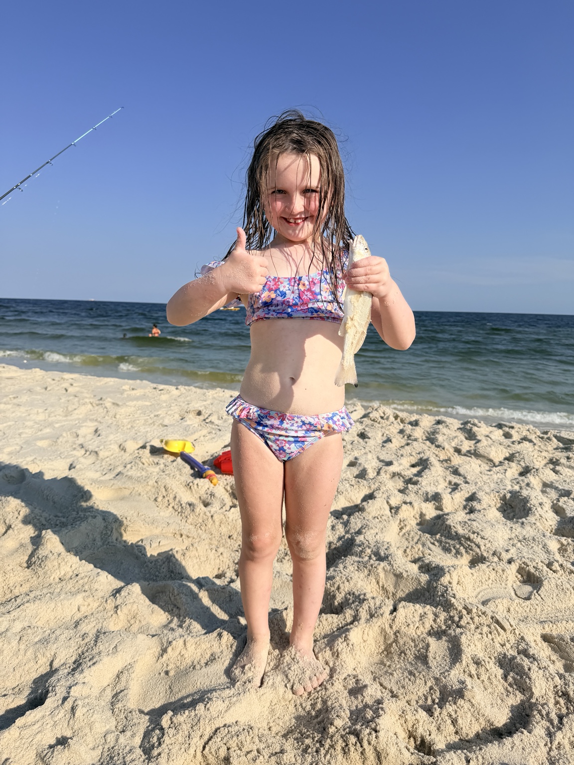 Young girl proudly holding a whiting caught from the beach