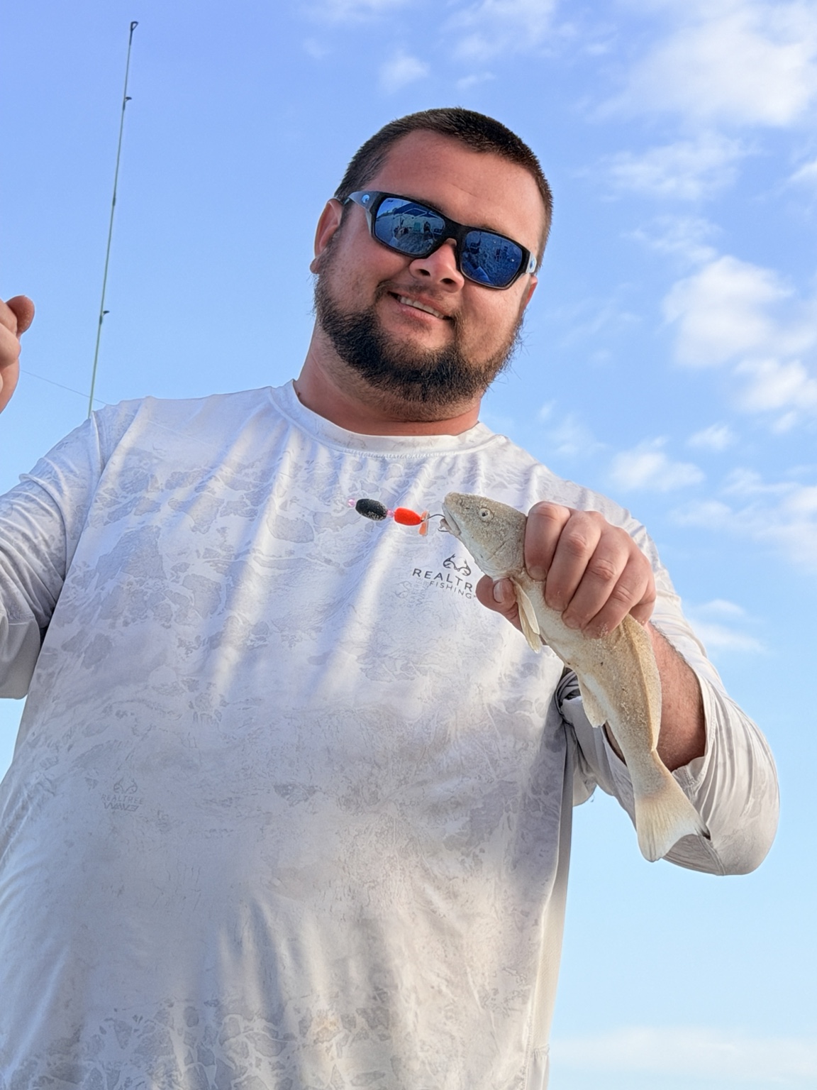 Surf angler holding a fish caught on a bright double-drop rig